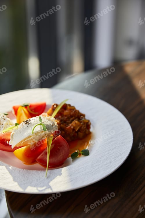 Preview: delicious eggplant caviar with tomato and butter served in restaurant on wooden table in sunlight