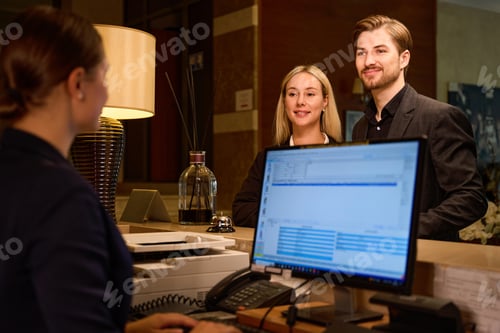 Preview: Receptionist typing on computer while couple standing at reception desk
