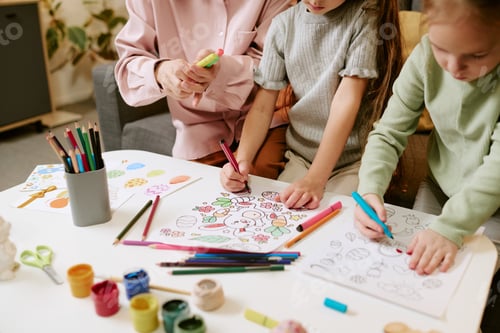 Preview: Girls and Senior Woman Coloring Easter Pictures Together Indoors