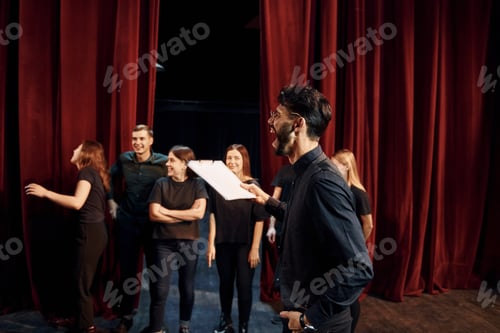 Preview: Group of actors in dark colored clothes on rehearsal in the theater