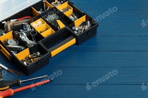 Preview: Plastic box with different furniture fittings and tools on blue wooden table, space for text