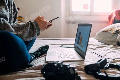 Preview: Person working on laptop in a cozy bedroom setting.