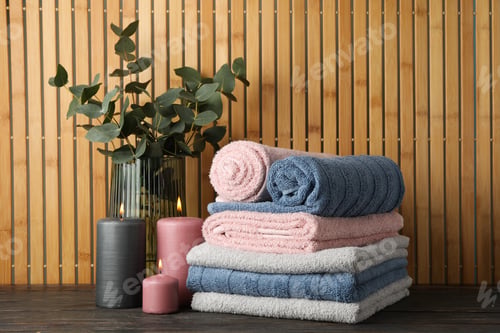 Preview: Towels, candles and eucalyptus on wooden table against bamboo background, space for text