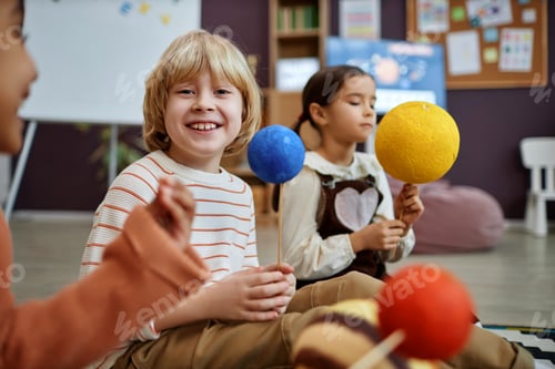 Preview: Cute blonde boy holding planet model in preschool class