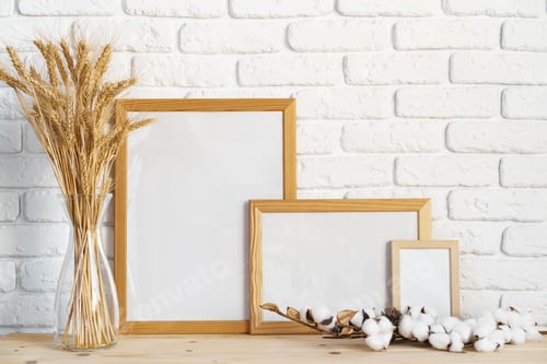 Preview: Vase with ears of wheat and photo frames against brick wall