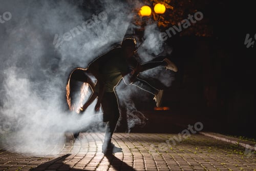 Preview: The man hold a woman on the dark street with a fume. night time