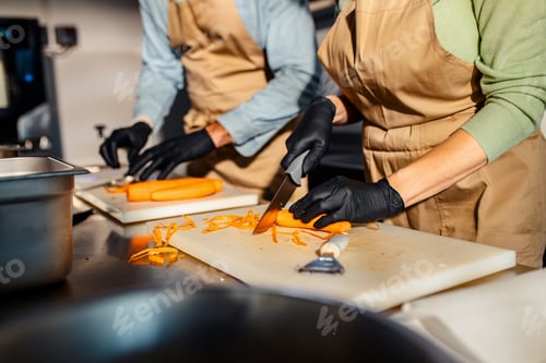 Preview: Close up of couple hands at cooking class cutting carrot preparing for a meal in the kitchen.