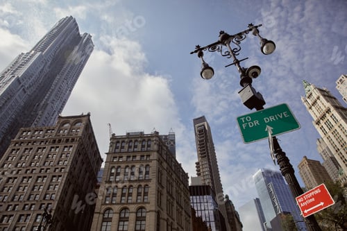 Preview: street pole with lanterns and traffic signs against skyscrapers in new york city, low angle view