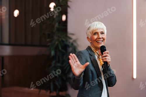 Preview: Smiling senior woman giving a speech over the microphone, smiling and talking.