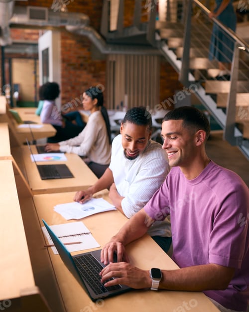 Preview: Two Businessmen With Laptop Meeting In Office Discussing Documents With Colleagues In Background