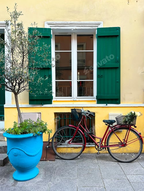 Preview: Bicycle Standing in Front of Yellow Wall Green Opened Window Geometric Pattern with Green Pot Plant