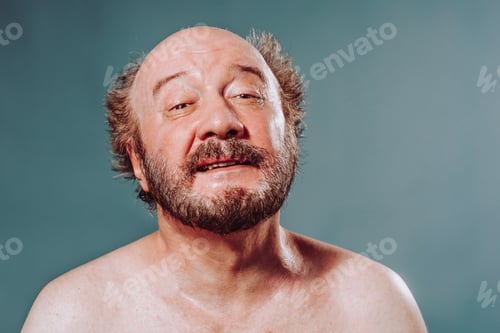 Preview: Front view studio blue isolated elderly man in a good mood, smiling joyful eyes naked torso bald