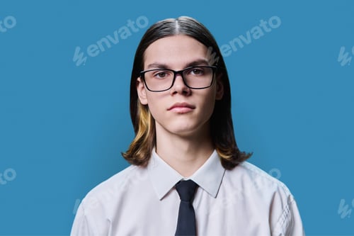 Preview: Headshot portrait of serious teenage guy on blue studio background