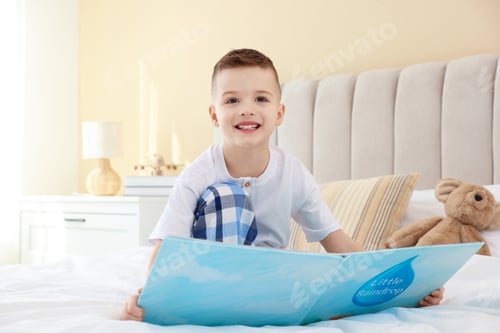 Preview: Bedtime. Cute boy with teddy bear reading book on bed indoors