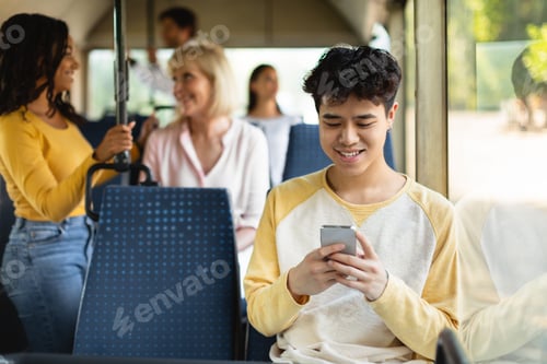 Preview: Happy Asian guy using cell phone in bus