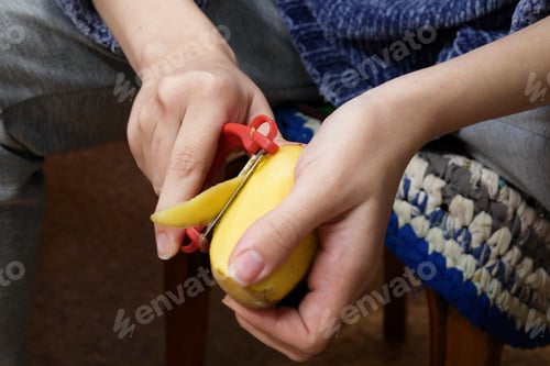 Preview: Woman peels potatoes while sitting on a chair in the kitchen
