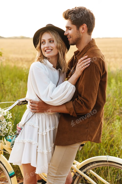Preview: Image of young couple hugging while riding bicycle in countryside