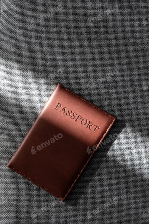 Preview: Brown leather passport cover on textured fabric in sunlight