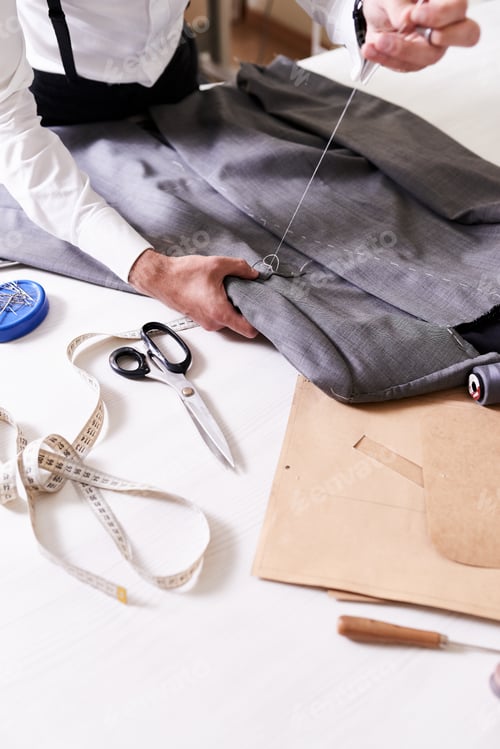 Preview: Tailor Sewing Gray Fabric in Bright Studio