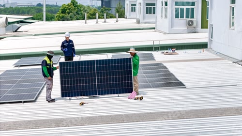 Preview: Aerial view of a rooftop with solar panels, showing a technician in safety performing maintenance.
