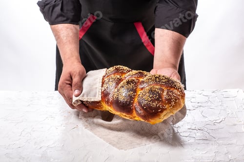Preview: Baker holding fresh baked challah jewish bread. Israeli authentic food