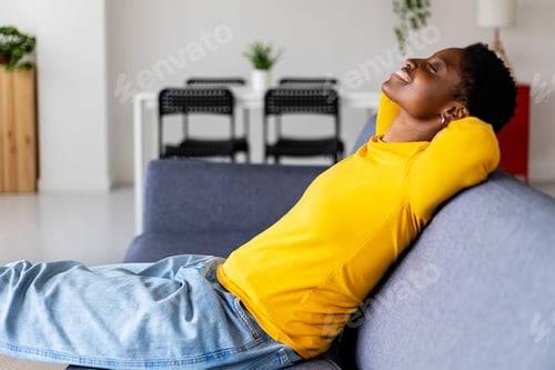 Vista previa: Cheerful young african american woman relaxing on sofa at home