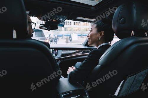 Preview: Cheerful multiracial colleagues discussing business project in car