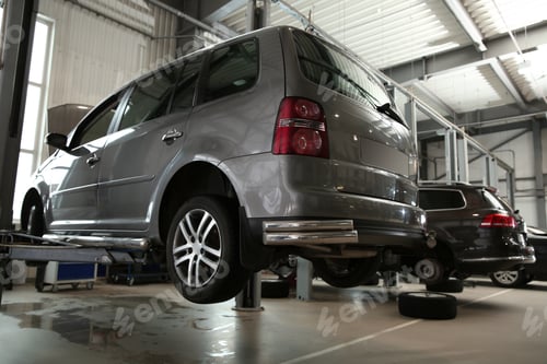 Preview: Modern car on hydraulic lift at automobile repair shop