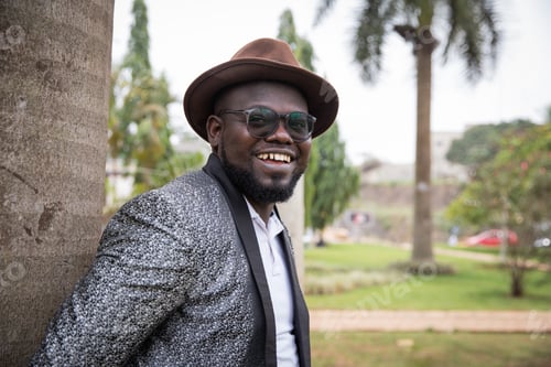 Preview: Stylish african businessman looks smilingly around in the park. Outdoor concept