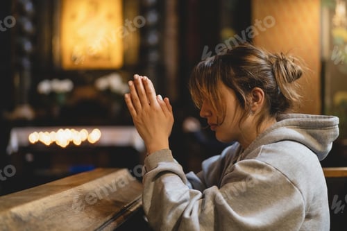 Preview: Woman praying on her knees in an ancient Catholic temple to God.