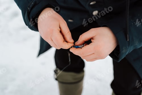 Preview: Close-up of male fisherman preparing fish bait, outdoors. Winter fishing, sports and active leisure