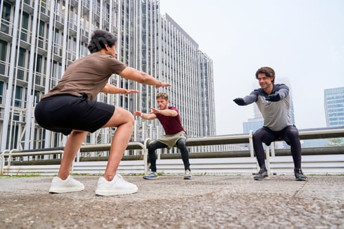 Preview: Three men doing squats outdoors in urban environment