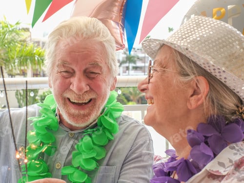 Preview: Cheerful elderly couple celebrating a birthday in a festive and colorful setting