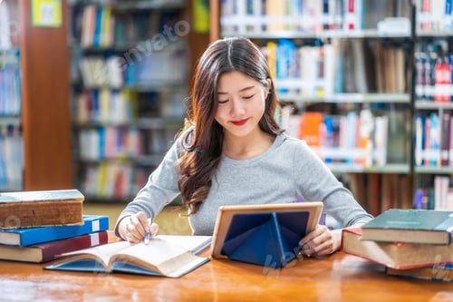 Preview: Asian young Student in casual suit doing homework and using technology teblet