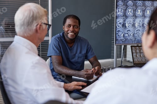 Preview: Smiling Black Man Talking to Colleagues during Working Meeting at Medical Office