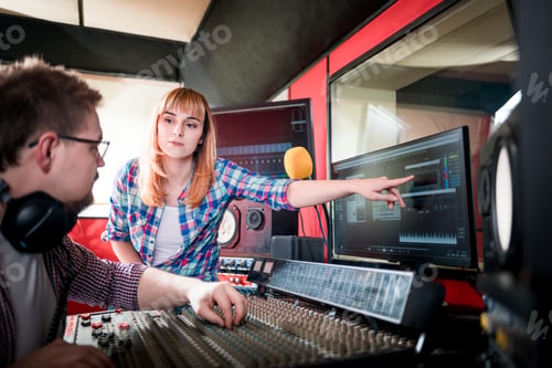 Preview: Music engineer and musician working together in recording studio using mixing desk