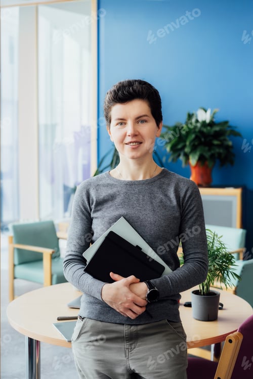 Preview: Portrait of smiling middle aged woman in casual outfit with digital tablet and notebook in office