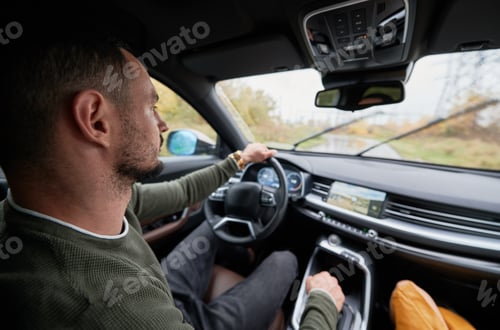Preview: Serious young man driving car, looking straight at road.