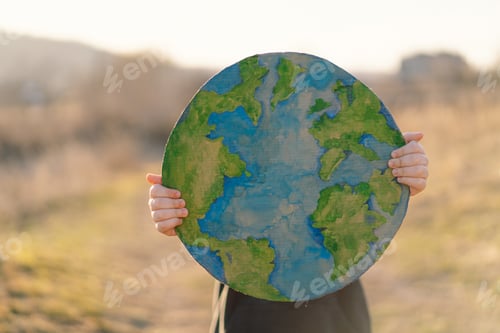 Preview: Little boy holding planet in hands against green spring background. Earth day