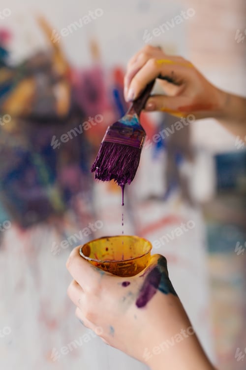 Preview: Close up photo of woman hands in paints holding paintbrush prepa