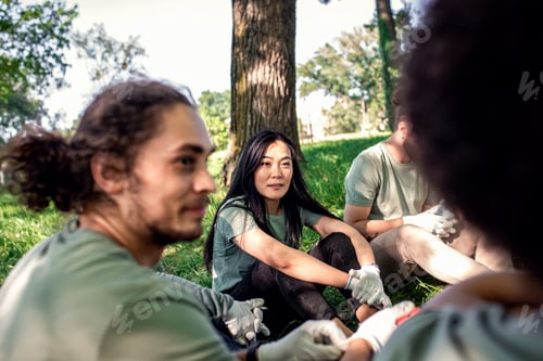 Preview: Multiethnic group of volunteers resting after cleaning city park.