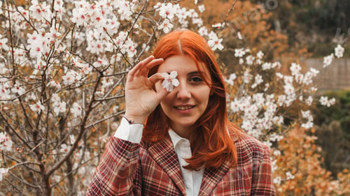 Preview: Happy red-haired girl under spring flower tree. Spring mood.