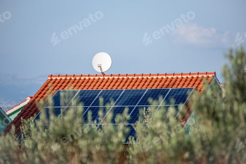 Preview: Solar panels on a tiled roof with satellite dish in rural setting