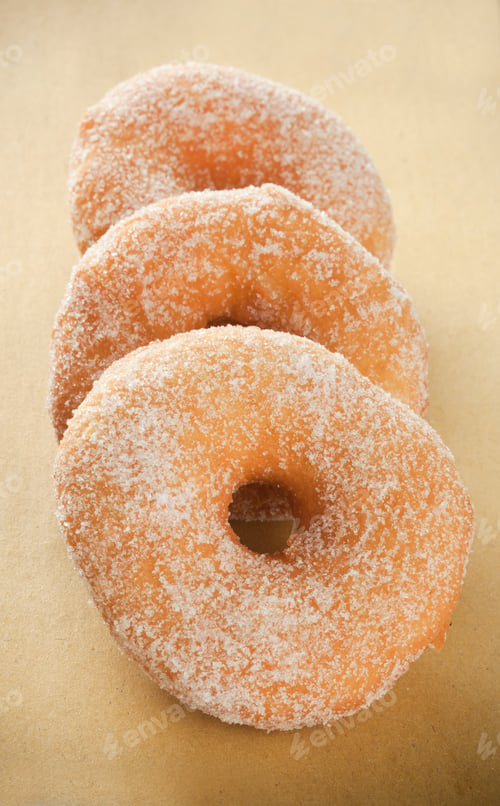 Sugared Donuts Stacked on Tan Background