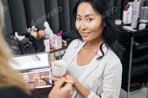 Preview: Elegant woman in white clothes enjoying great time in modern bright salon