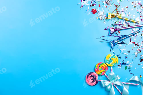 Preview: a top view colorful lollipops with pink-white sticks blue bow along with birthday decors on the blue
