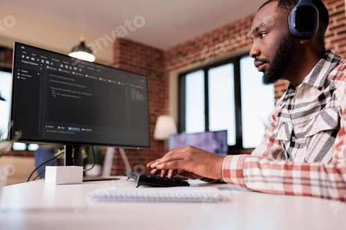 Preview: Database developer with wireless headphones programming algorithm using personal computer