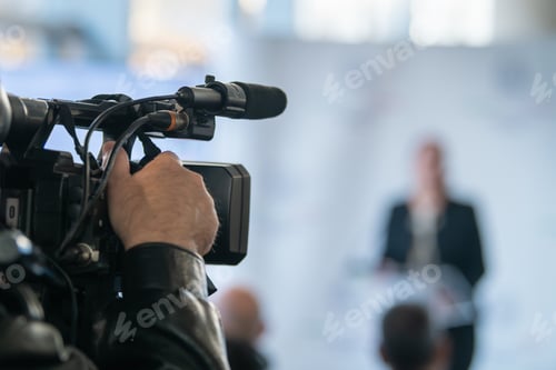Preview: TV camera focused on podium during press briefing. Highlights communication accuracy