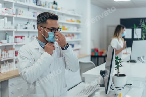 Visualização: Farmacêutico com máscara protetora no rosto enquanto trabalhava em uma farmácia