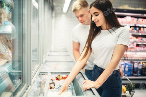Preview: Young couple choosing frozen goods in supermarket